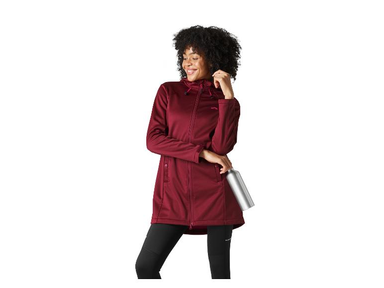 Femme souriante en veste longue bordeaux et leggings noirs, tenant une bouteille d'eau argentée.