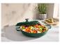 Cocotte verte remplie de légumes coupés sur un comptoir.