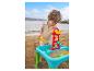Enfant jouant avec une table à sable et à eau sur la plage.