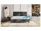 Un lit gris avec un matelas en mousse à plusieurs couches.