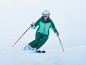 Une femme en tenue de ski skie avec des skis et des bâtons.