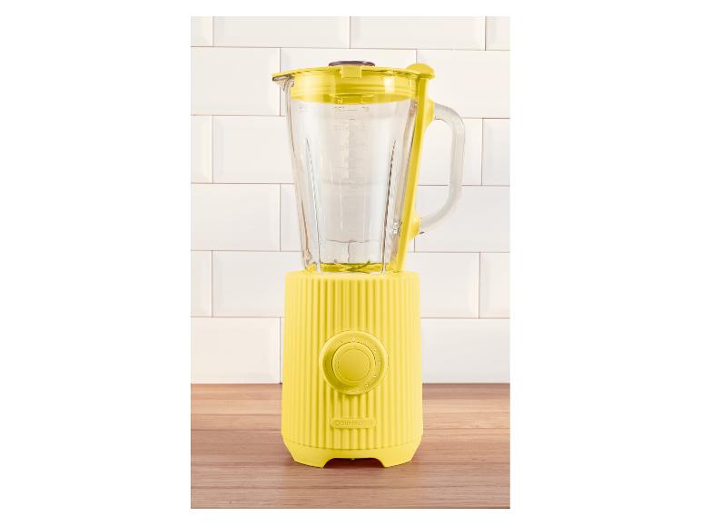 Mixeur jaune SILVERCREST avec pichet en verre, sur un comptoir en bois et des carreaux blancs.