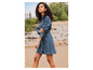 Une femme porte une robe en jean sur une plage de sable.