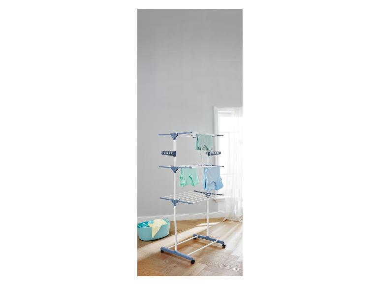 Séchoir à linge blanc et bleu à trois niveaux avec un panier à linge bleu.