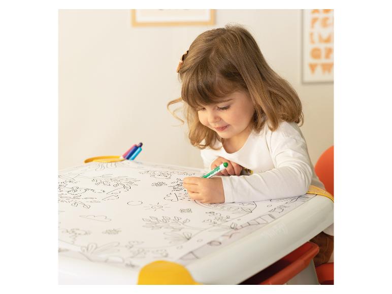 Petite fille coloriant un livre sur une table avec un marqueur vert.
