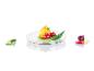 Un poivron jaune, des tomates, des oignons verts et un concombre sur un plat transparent.