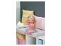 Poupée BABY born aux cheveux blonds, t-shirt rose et jupe arc-en-ciel, assise sur un banc.