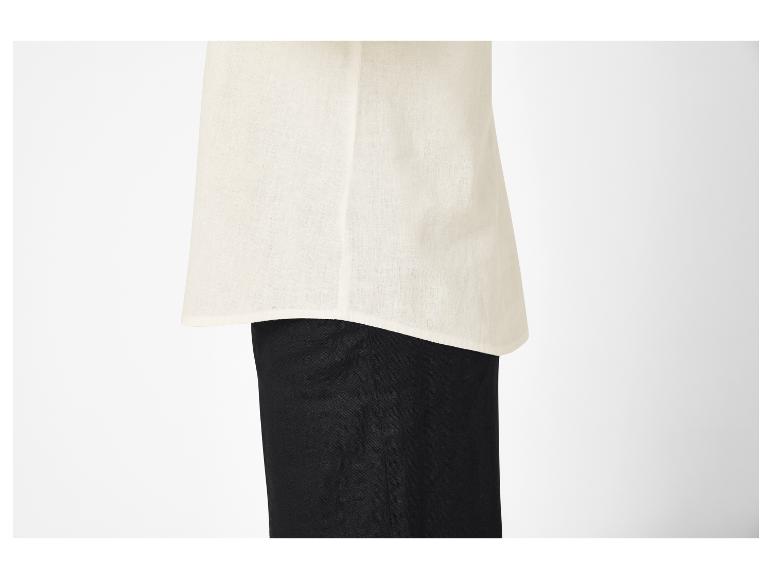 Gros plan d'une personne portant un haut en lin crème sur un pantalon noir.