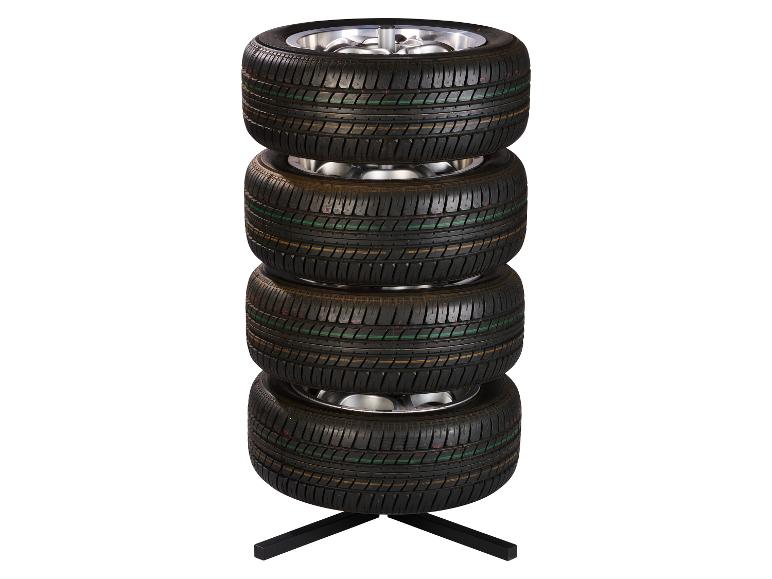 Quatre pneus empilés avec jantes sur un support noir.