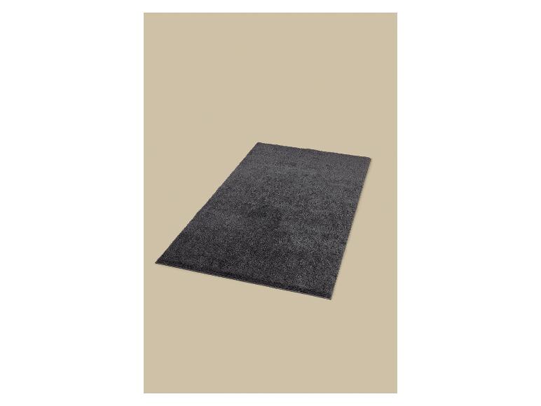 Tapis de bain gris foncé sur fond beige.