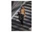 Une femme portant un pull beige et un pantalon noir monte les escaliers.