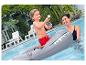 Garçon sur matelas requin avec pistolet à eau dans la piscine avec une femme.
