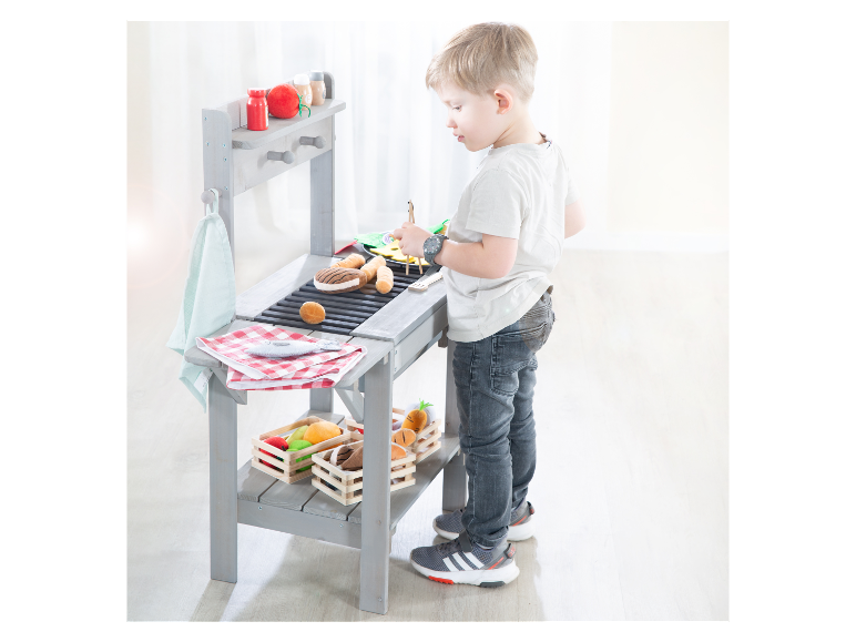 Enfant jouant avec un barbecue en bois jouet.