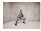 Un homme fait des squats avec un kettlebell dans une salle de sport.