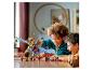Deux enfants jouent avec un dragon Lego Ninjago et des figurines sur une table.