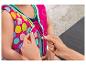 Une personne zippe un gilet de natation rose à pois colorés sur un enfant.