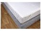 Un matelas blanc avec une housse grise sur un sol en bois