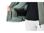 Personne montrant l'intérieur d'une veste verte avec un sous-vêtement noir et un pantalon blanc.