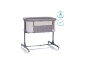 Lit bébé gris avec côtés en maille et roulettes, adapté dès la naissance.