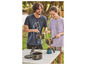 Un couple cuisine dehors avec une cuisinière à gaz et des casseroles.