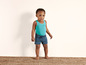 Un jeune garçon portant un débardeur turquoise et un short bleu à motifs ondulés.