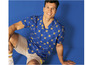 Homme portant une chemise bleue à imprimé LIDL et un short.