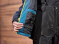 Gros plan sur une veste de ski noire avec des détails bleus et un pantalon assorti.