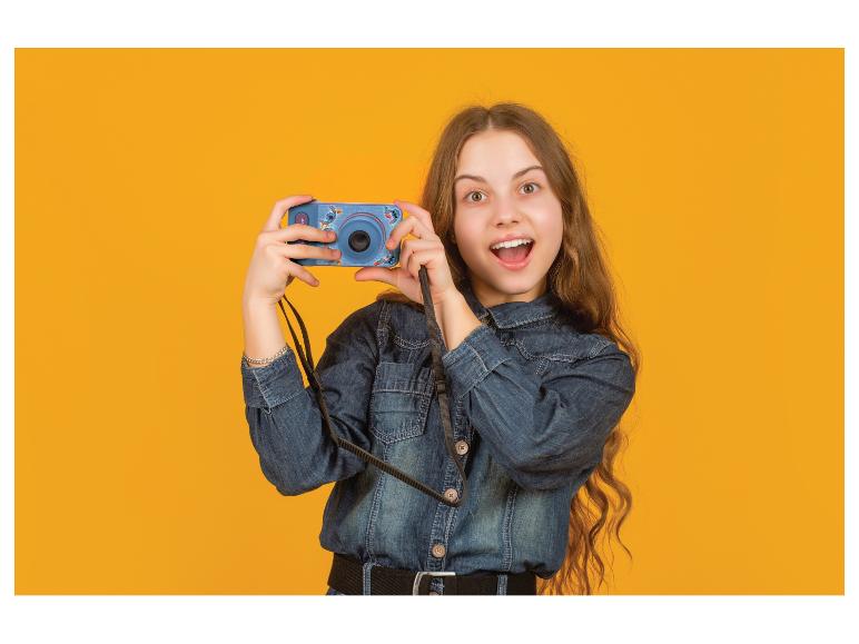 Fille heureuse en chemise en jean tenant un appareil photo bleu avec motif Stitch.