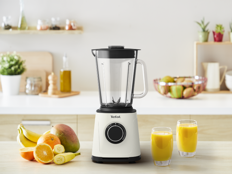 Mixeur avec des fruits frais et deux verres de jus sur un comptoir de cuisine.