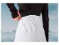 Pantalon de ski blanc avec sous-vêtements thermiques noirs, sur fond de montagnes.