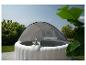Spa gonflable avec auvent, deux boissons et fond de jardin verdoyant.