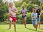 Des enfants courent pieds nus sur une pelouse.