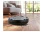 Aspirateur robot sur un parquet avec de la saleté, dans un salon.