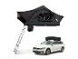 Tente de toit grise avec échelle déployée et voiture blanche avec tente de toit pliée.