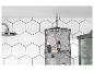 Un panier en fil noir avec des produits L'Occitane dans une salle de bain avec des carreaux hexagonaux blancs.
