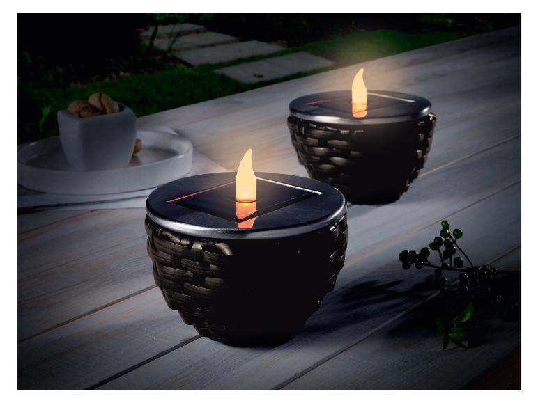 Deux bougies solaires noires sur une table en bois.