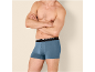 Homme en caleçon bleu, bras croisés.