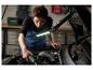 Une personne travaille sur une voiture avec un tournevis et une lampe de travail Parkside.