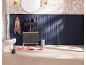 Salle de bain avec meuble-lavabo noir, toilettes, tapis floral et mur lambrissé bleu marine.