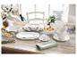 Vaisselle blanche en porcelaine sur une table en bois rustique, avec des fruits et des fleurs.