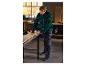Homme en tenue de travail Parkside mesurant une planche de bois dans un atelier.