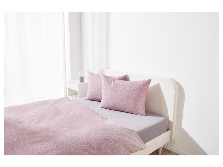 Un lit avec de la literie rose clair.