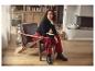 Femme en col roulé noir et pantalon rouge, assise dans un fauteuil en cuir.