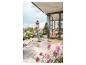 Femme nettoyant une terrasse avec un nettoyeur haute pression, entourée de plantes et d'une maison moderne.