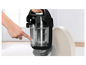 Une main pointe le bouton pour vider l'aspirateur.