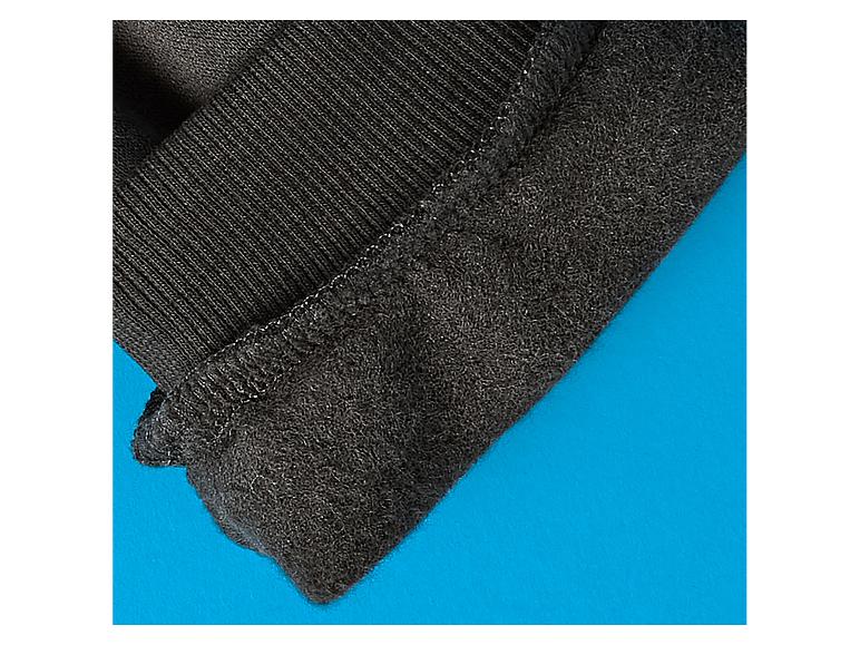 Gros plan d'un tissu thermique noir avec bord côtelé sur fond bleu.