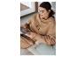 Une femme en sweat-shirt à capuche beige et pantalon de survêtement de U.S. Polo Assn. lit un magazine.