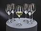 Six verres avec un bord doré, un rempli de vin blanc.