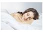 Une femme dort dans des draps blancs.