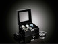 Six montres dans un coffret en cuir noir avec un couvercle en verre.